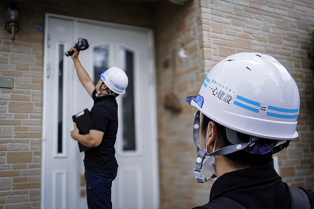 戸建住宅の外壁を点検する一心建設の住宅診断スタッフ